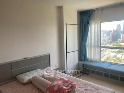 Bright bedroom with city view, featuring a cozy bed and large window seating area.