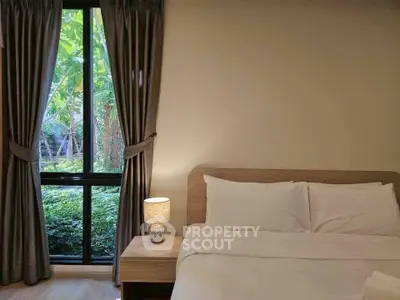 Cozy bedroom with large window and garden view, featuring elegant curtains and a stylish bedside lamp.