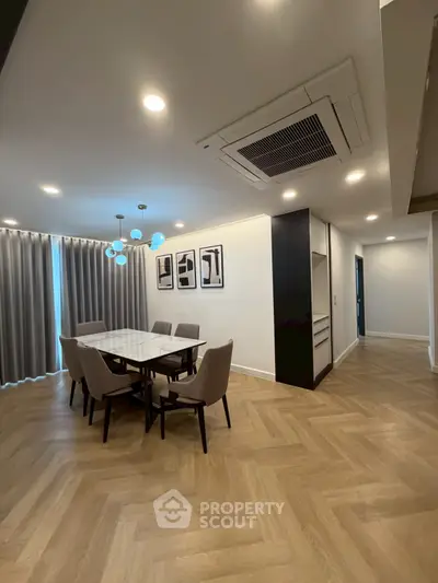 Elegant dining area with modern lighting and herringbone flooring in a stylish apartment.