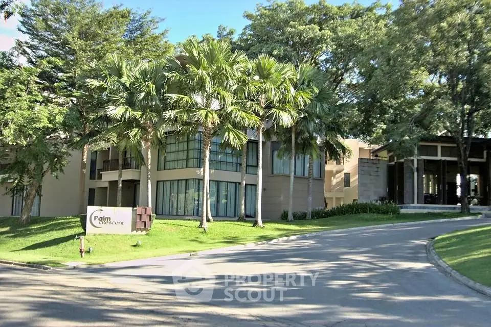 Luxurious modern building surrounded by lush greenery and palm trees, offering a serene and upscale environment.