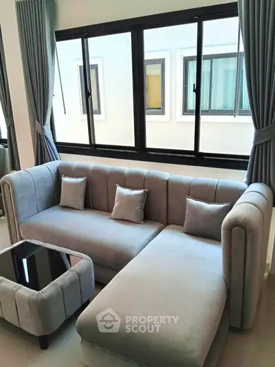 Modern living room with stylish gray sofa and large windows, perfect for relaxation and natural light.