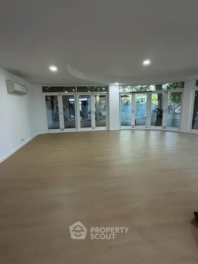 Spacious living room with wooden flooring and large windows for natural light.