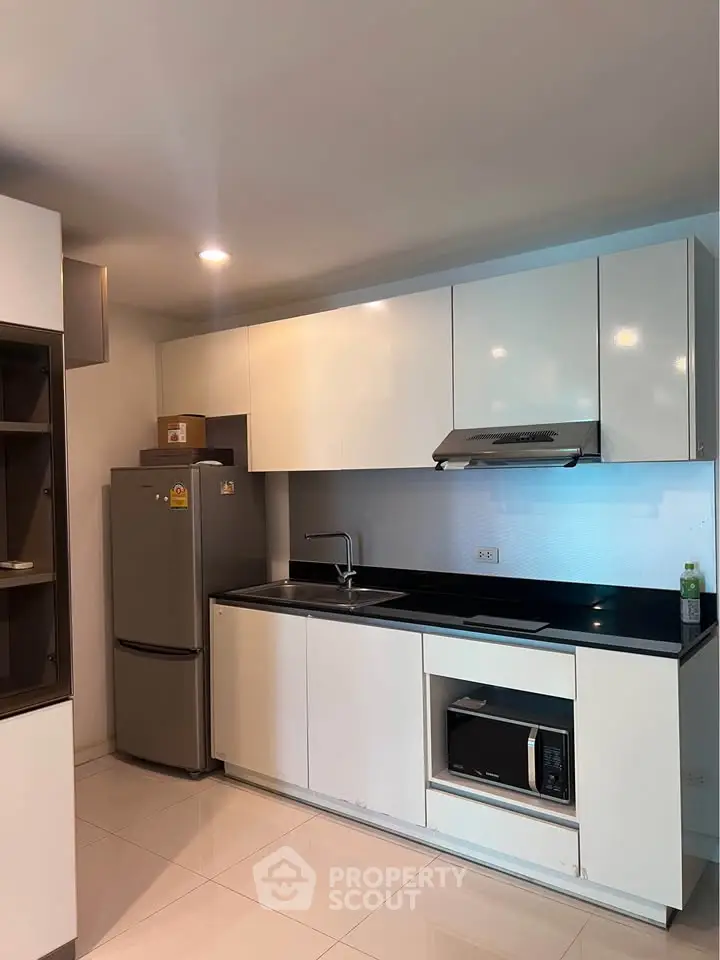 Modern kitchen with sleek white cabinets and stainless steel appliances in a contemporary apartment.