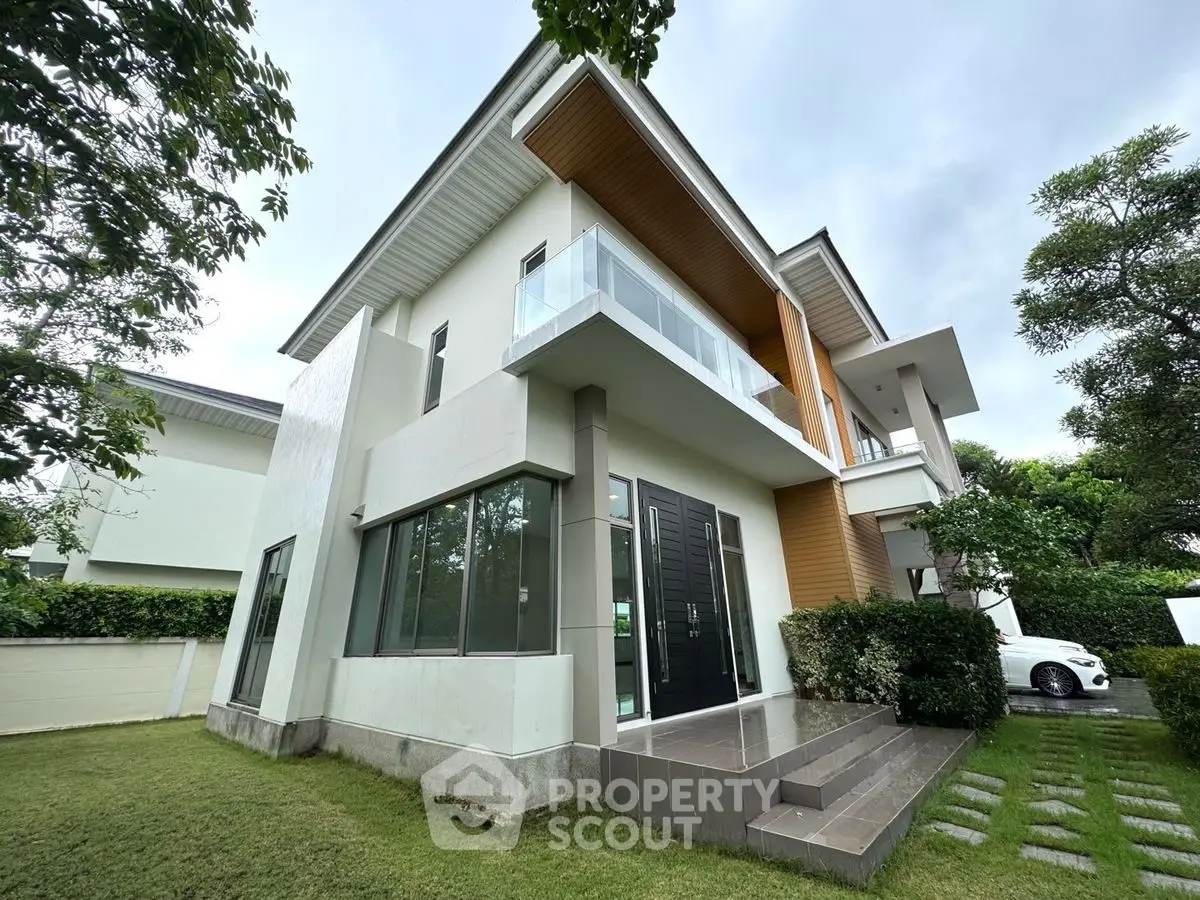 Modern two-story house with balcony and lush garden