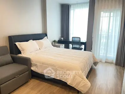 Modern bedroom with stylish decor and natural light, featuring a cozy bed and work desk.
