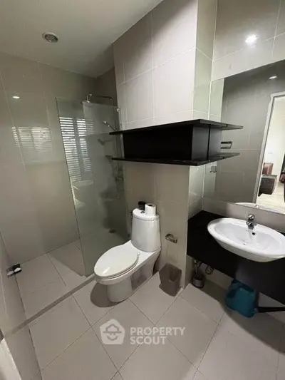Modern bathroom with sleek design, featuring glass shower and contemporary fixtures.