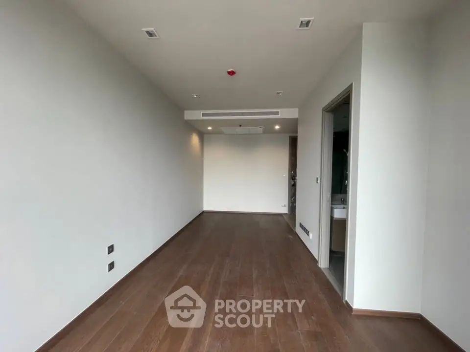 Spacious unfurnished room with wooden flooring and modern lighting, ideal for customization.