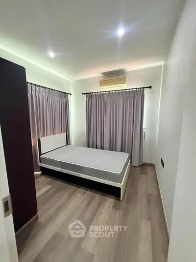 Modern bedroom with minimalist design, featuring a bed, curtains, and air conditioning.