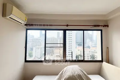 Spacious bedroom with city view, featuring large windows and air conditioning, perfect for urban living.