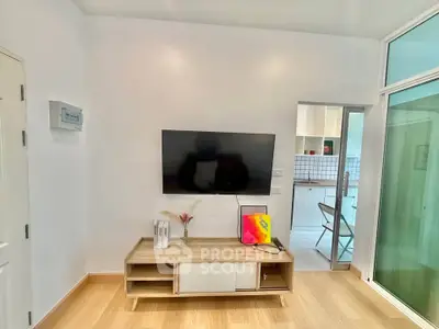 Modern living room with wall-mounted TV and stylish wooden cabinet, open view to kitchen area.