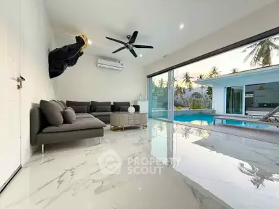 Luxurious living room with pool view and modern furnishings in tropical setting.