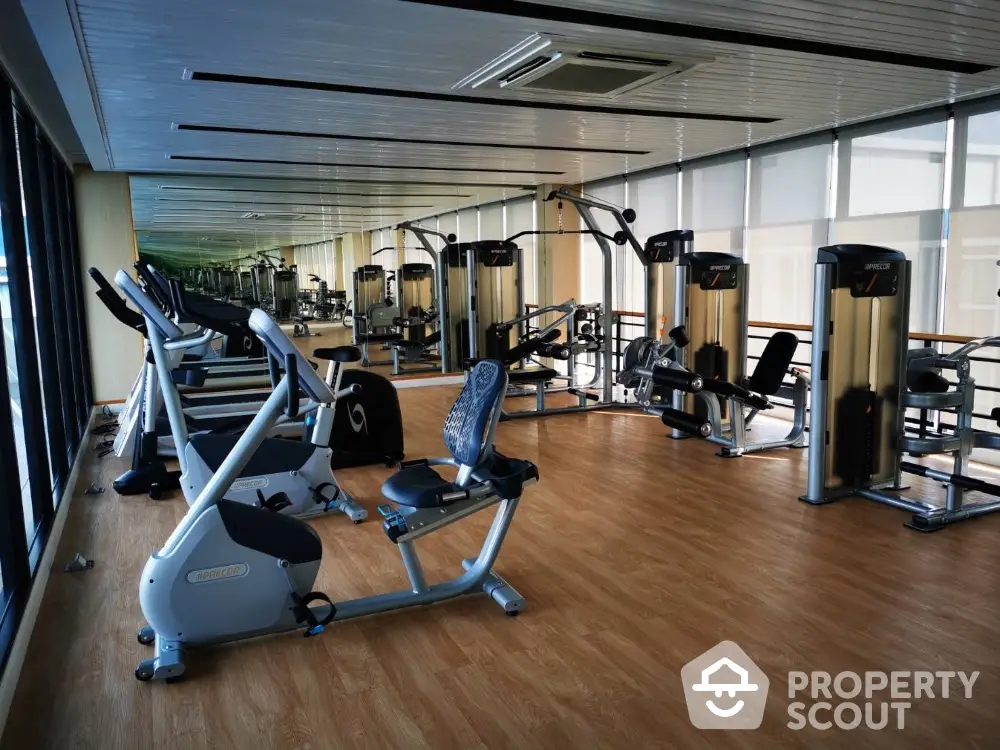 Spacious modern gym with state-of-the-art fitness equipment and wooden flooring.