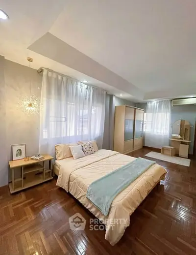 Spacious bedroom with elegant decor and large windows for natural light.