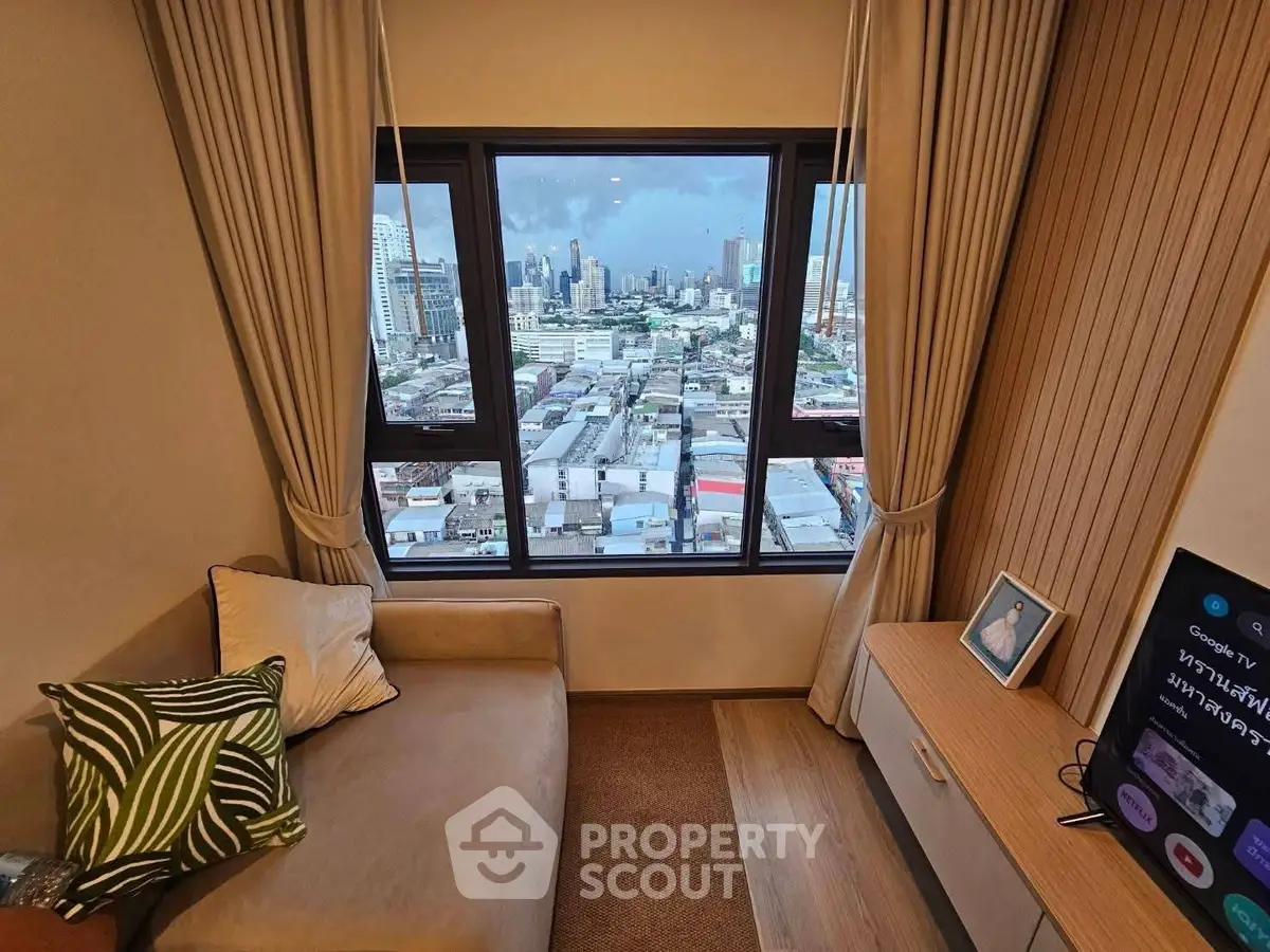 Cozy living room with stunning city view from large windows, featuring a comfortable sofa and modern decor.