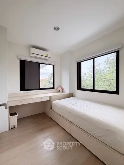 Bright minimalist bedroom with large windows and built-in furniture, offering serene views.