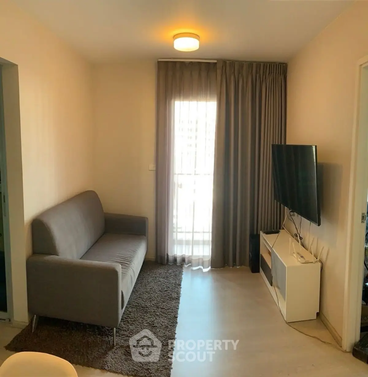 Cozy living room with modern sofa and wall-mounted TV, perfect for relaxation.