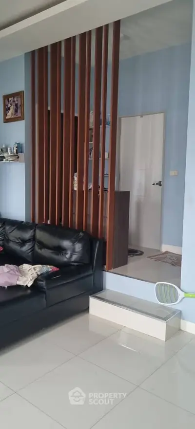 Modern living room with sleek black leather sofa and stylish wooden partition