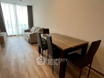 Spacious living room with modern dining set and cozy sofa, featuring floor-to-ceiling windows for natural light.