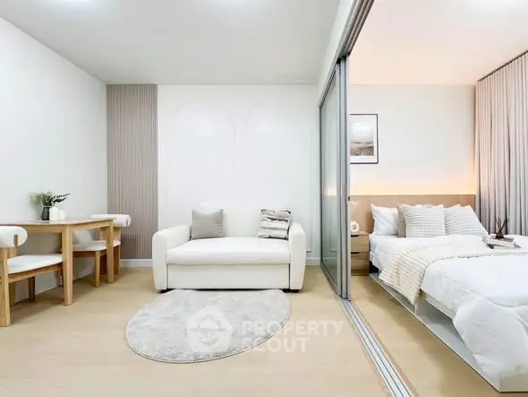 Modern studio apartment with cozy living area and stylish bedroom separated by glass partition.