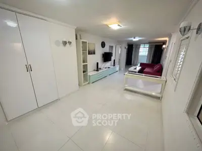 Spacious living room with modern decor and ample natural light, featuring a sleek entertainment unit and comfortable seating.