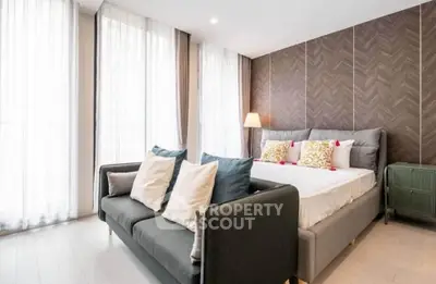 Luxurious bedroom with elegant decor and natural light, featuring a stylish sofa and modern design elements.