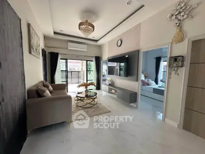 Elegant living room with modern decor, featuring a chandelier, wall-mounted TV, and access to a balcony.