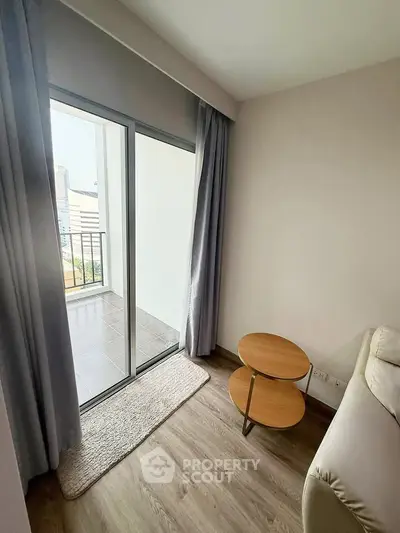 Cozy living room with sliding glass doors leading to a balcony, featuring a small round table and modern decor.