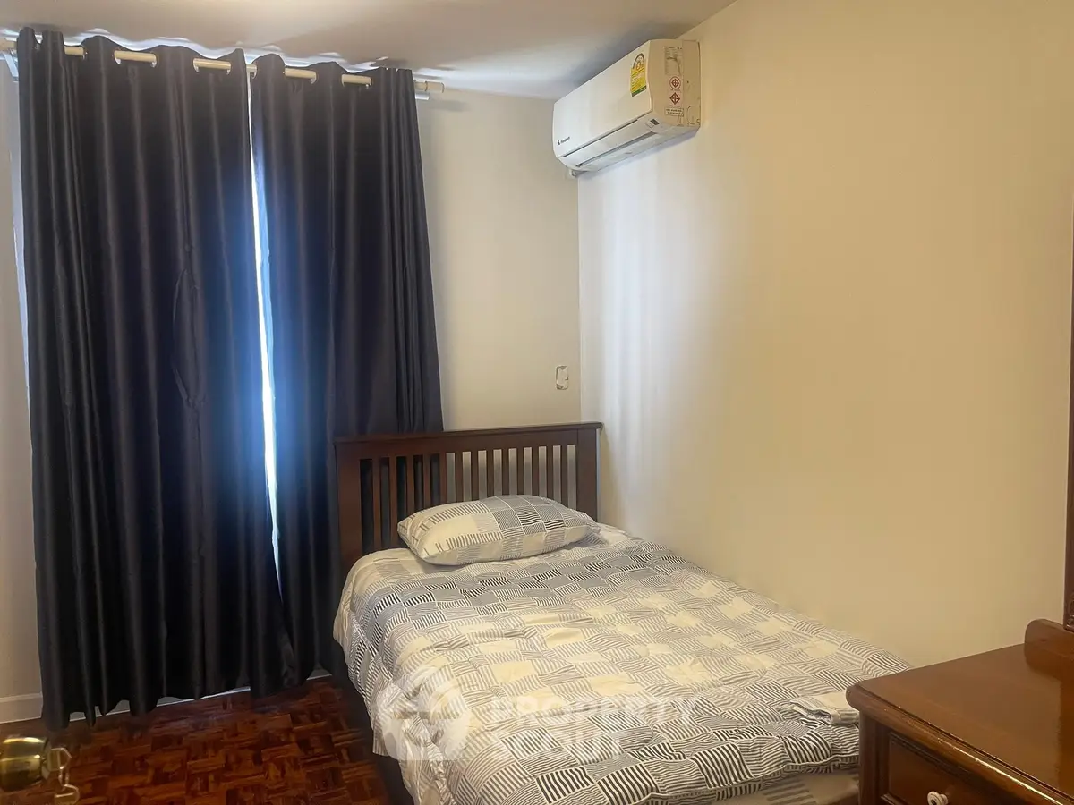 Cozy bedroom with single bed, wooden furniture, and air conditioning, perfect for a comfortable living space.