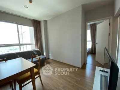 Modern apartment living room with wooden flooring and large windows offering natural light.