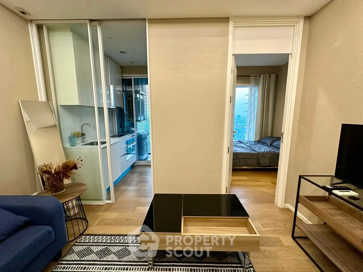 Modern apartment interior with open living room and kitchen layout, featuring sleek furniture and city view.