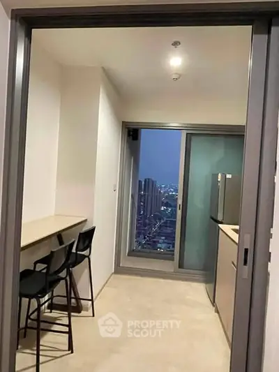 Modern kitchen with city view, sleek design, and breakfast bar seating in high-rise apartment.