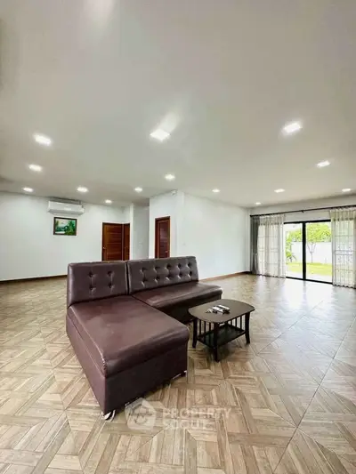 Spacious living room with modern L-shaped sofa and large windows offering natural light.
