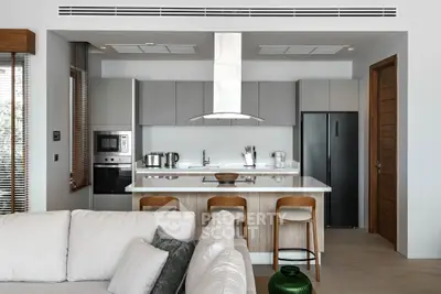 Modern kitchen with sleek cabinetry and breakfast bar in open-plan living space.