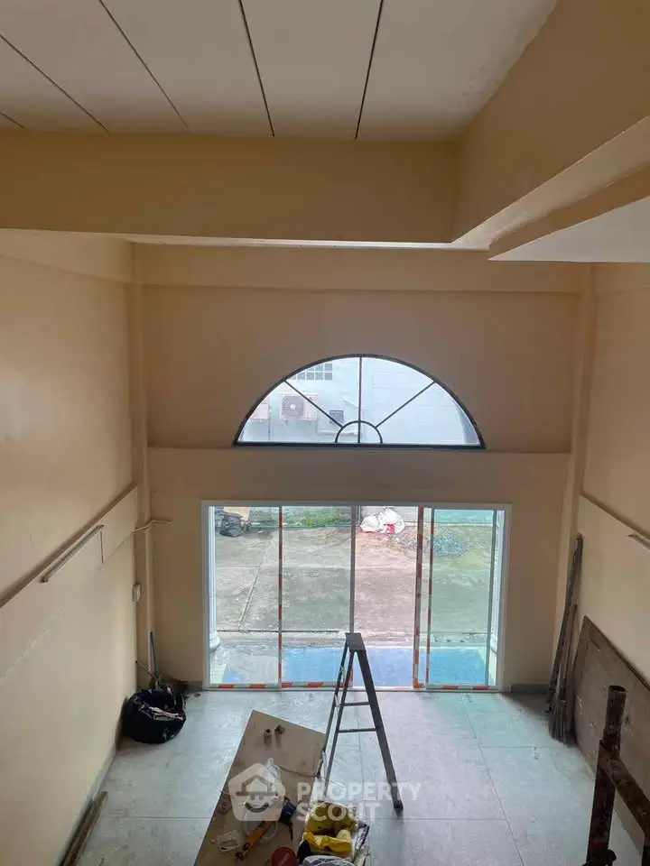 Spacious interior with high ceiling and large window, ideal for natural light.