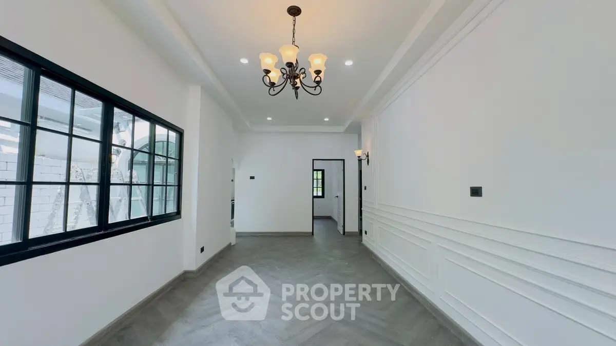 Spacious empty room with elegant chandelier and large window