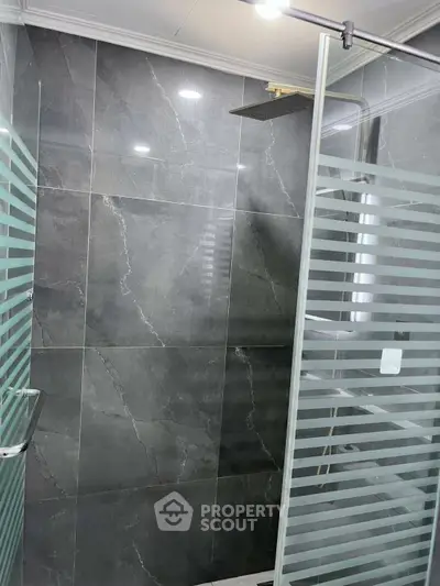 Modern bathroom with sleek glass shower and elegant gray tiles