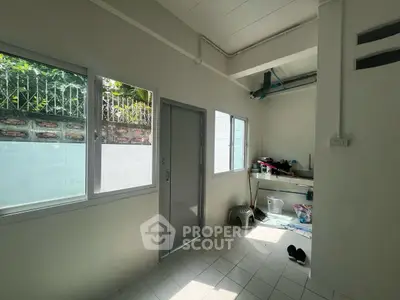 Bright utility room with tiled floor and large windows, ideal for storage or laundry.