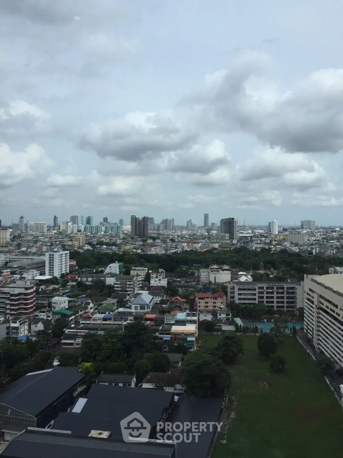 Stunning cityscape view from high-rise building showcasing urban skyline and lush greenery.