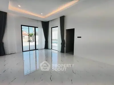 Spacious modern living room with marble flooring and large windows offering pool view.