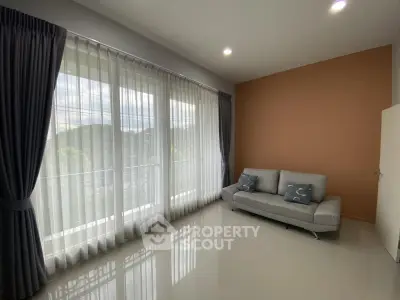 Spacious living room with large windows and modern sofa, offering abundant natural light and serene views.