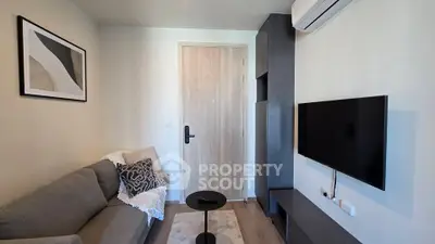 Cozy living room with modern decor, wall-mounted TV, and air conditioning unit.