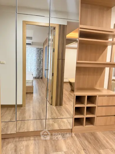 Spacious bedroom with mirrored wardrobe and wooden flooring in modern apartment.