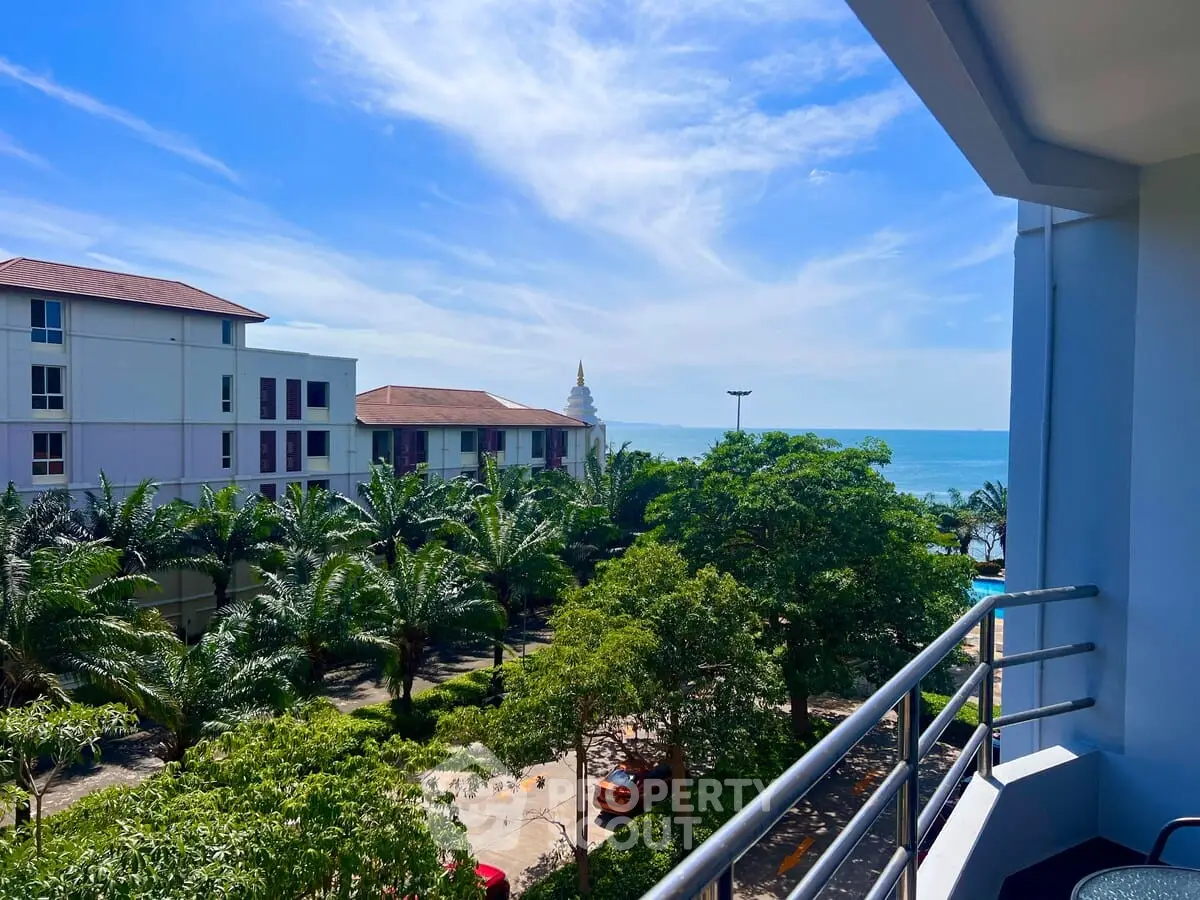 Stunning ocean view from a modern balcony overlooking lush greenery and distant buildings.