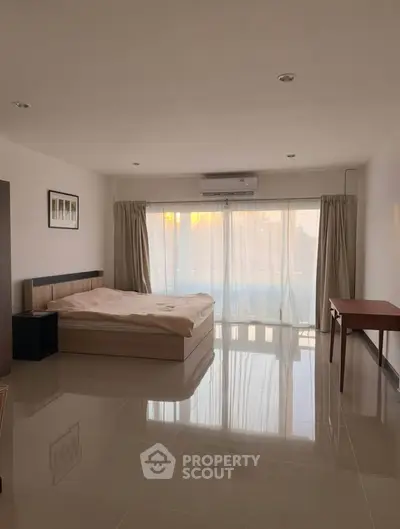 Spacious bedroom with large windows and modern furnishings in a bright apartment.