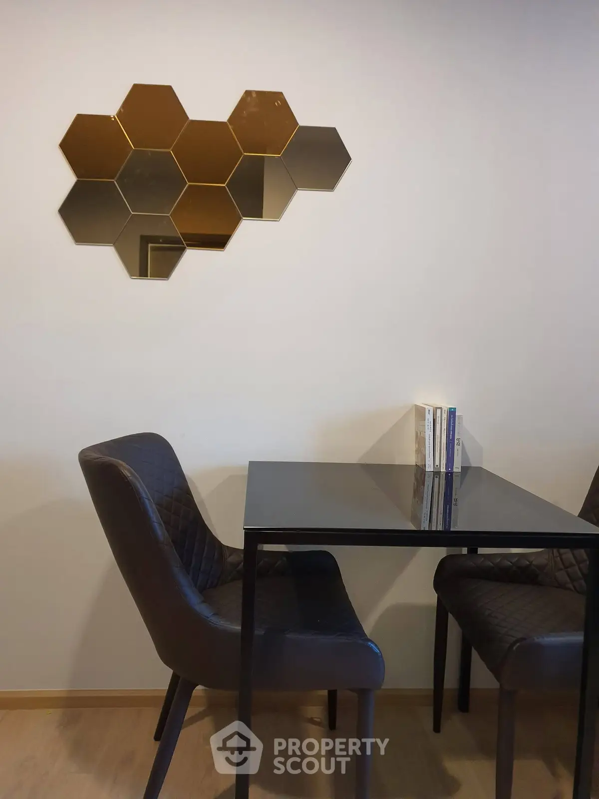 Modern dining area with stylish hexagonal wall decor and sleek black chairs.