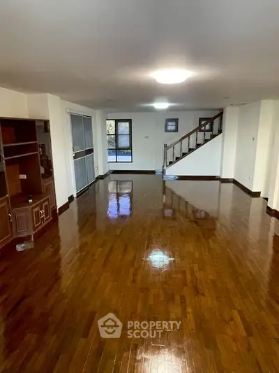 Spacious living room with polished wooden floors and staircase in elegant home.