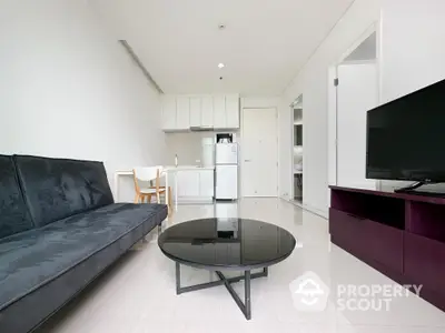 Sleek modern studio apartment with open layout, featuring a stylish kitchen, plush sofa, and a chic coffee table, perfect for urban living.