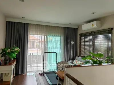 Charming living room with balcony access, featuring cozy seating and natural light.