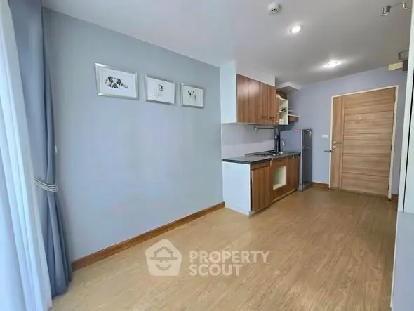 Modern compact kitchen with wooden cabinets and sleek design in a bright apartment.
