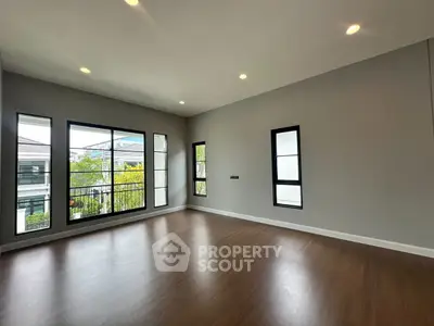 Spacious empty room with large windows and wooden flooring